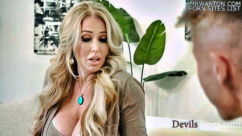 Blonde MILF with huge tits in low-cut top shows massive cleavage seducing man on couch