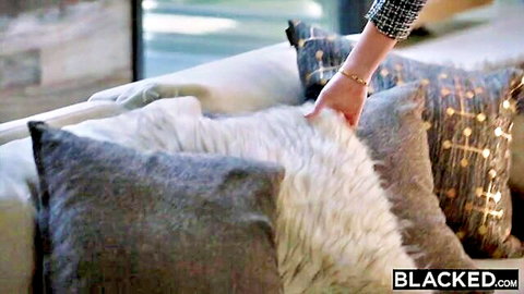 Woman's hand in plaid sleeve grabbing fluffy white fur pillow on luxury couch pillows