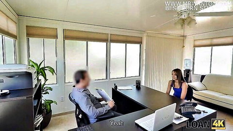Brunette babe in blue top smiling at office desk negotiating loan with suited man