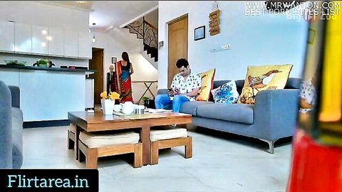 Desi aunt in red saree stands near nephew on sofa during game