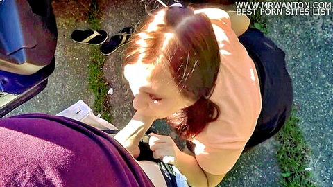 Redhead in pigtails gives outdoor blowjob by car in parking lot