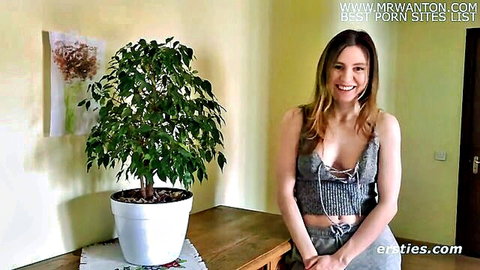 Lina smiles in low-cut grey top showing cleavage, casual solo tease