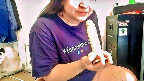 Curvy Asian woman teasing with large dildo in mouth, purple t-shirt, squirting tease
