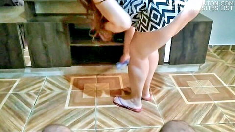 Brunette stepmom bending over in short patterned dress, teasing legs