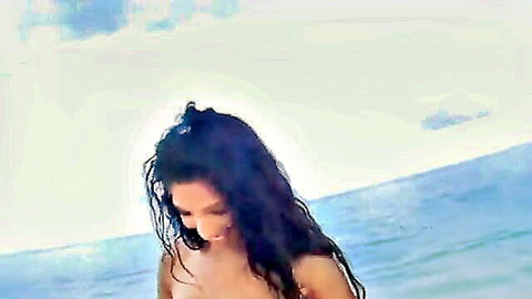 Topless tanned brunette with huge tits smiles with wet hair on sunny beach