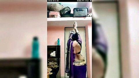 Seductive Indian woman in purple sari posing with arms raised, back exposed