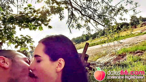 Skinny brunette teen passionately kissing mustached guy in public park outdoors