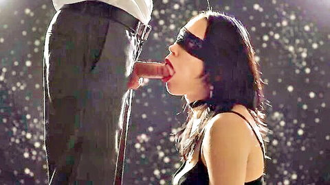 Blindfolded brunette kneels sucking big cock from suited man's unzipped pants in BDSM scene