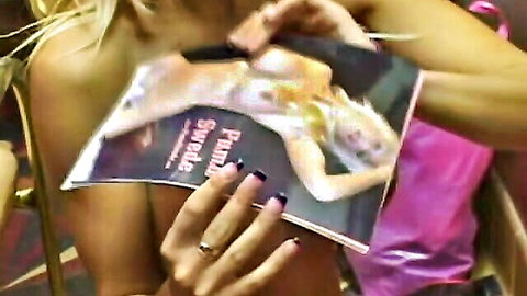 Blonde MILF holds magazine featuring Swedish babe's big shiny tits against her own bare chest