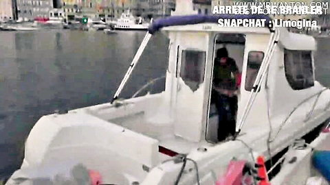 Caucasian man standing on white boat at French marina dock with other boats in background
