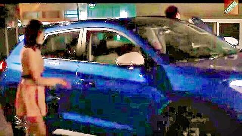 Asian woman in short red dress teasing near blue car at night, outdoor seduction