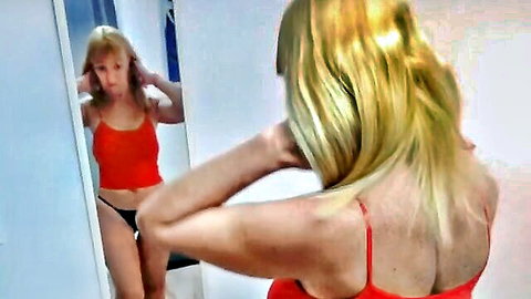 Blonde babe in red tank top and black thong shows off big ass in dressing room mirror while fixing hair