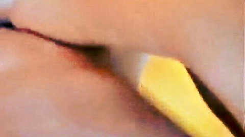 Close-up of woman's lips wrapped around yellow dildo in morning oral scene