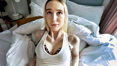 Blonde petite babe teasing with cleavage in white tank top and black lace bra POV on bed