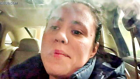 Latina woman smoking in car, close-up POV selfie with visible smoke