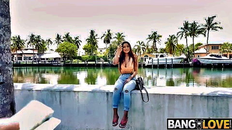 Numi Zarah in sexy orange crop top and ripped jeans by the water, outdoor tease