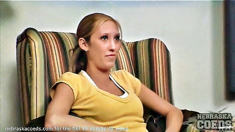 Skinny blonde coed in tight yellow tank top sits in chair for casting interview