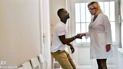 Blonde doctor in open lab coat shakes hands with BBC patient in hospital room