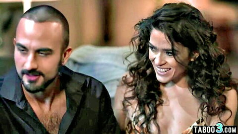 Brunette with huge cleavage smiles teasingly next to bald husband on couch taboo style