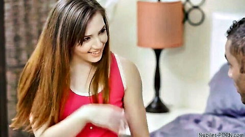 Riley Reid in pink tank top smiling at man on bed, Christmas sex doll tease