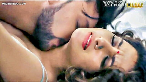 Indian couple in passionate embrace, man kissing curvy wife's neck in bed