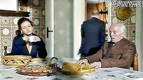 Seductive brunette in black dress with older man at table in classic adult scene