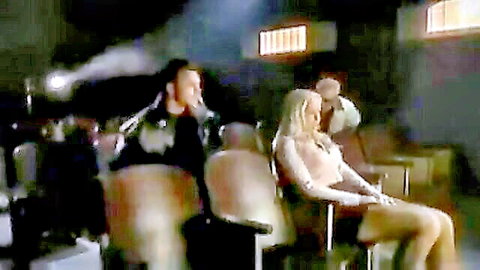 Blonde woman in low-cut top seduced by two men in dark cinema seats