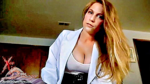 Blonde woman in white blazer displaying deep cleavage in seductive indoor tease