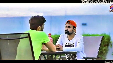 Two clothed South Asian men chatting face-to-face at outdoor table in amateur Indian video