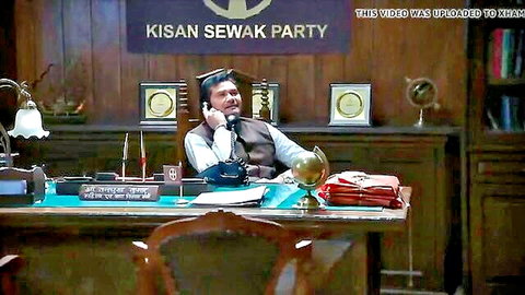 Indian man in vest sits at desk talking on phone in Kisan Sewak Party office