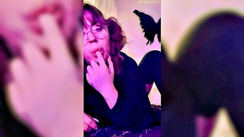 Goth brunette teen with glasses teases tongue out licking fingers seductively in purple glow
