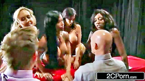 Bald man surrounded by topless busty blonde brunette and ebony women flashing huge tits in orgy