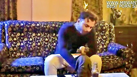 Indian man in black sweater with pants unzipped holding brown toy in lap