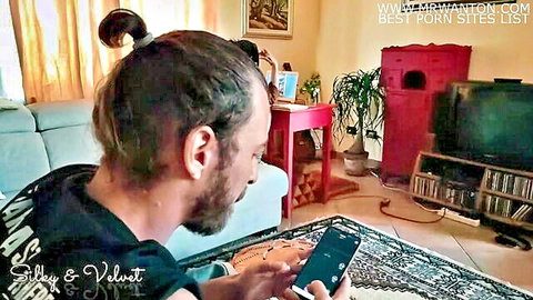 Bearded man with ponytail on teasing phone call with sex toys