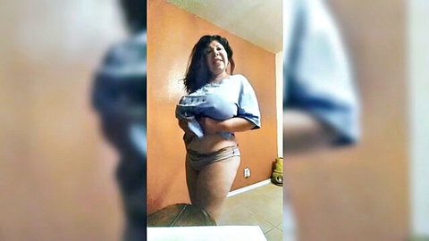 Curvy Latina woman lifting top to expose breasts, smiling seductively