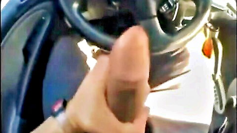 Woman's hand with red nails gripping thick erect cock near car steering wheel