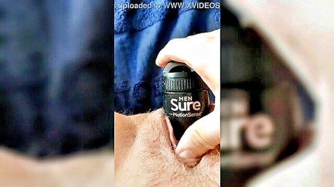 Man's hand spraying Sure Men deodorant on hairy balls and groin closeup