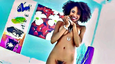 Nude African woman with curly hair smiling and posing seductively