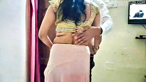 Indian bhabhi in gold blouse and pink saree embraced by man from behind