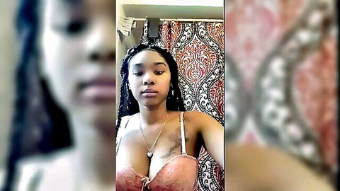 Ebony beauty with braids in pink lingerie, showing deep cleavage