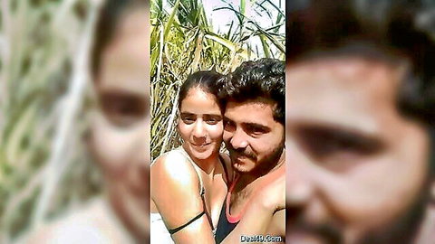Indian couple selfie in sugarcane field, woman in bikini top embracing bearded man