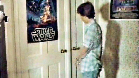 Young boy in checkered shirt standing in bedroom with Star Wars posters, 1983 Private Teacher scene