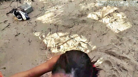 Man grips braided hair babe's head pushing down for beach blowjob on sandy outdoor spot