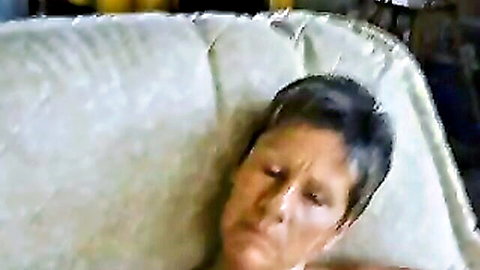 Mature housewife lying on couch with intense gaze, short dark hair