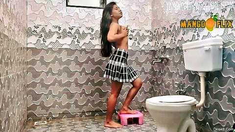 Topless Indian teen lifts pleated skirt in bathroom teasing bare tits and pussy on pink stool