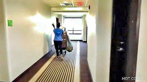 Latin maid in blue uniform walking hallway with cleaning bag