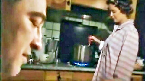 Man eyes curvy Italian housewife in pink striped nightgown stirring pot on kitchen stove
