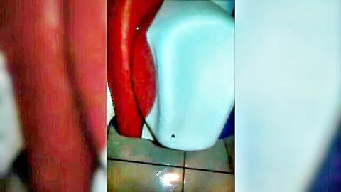 Thick red dildo leaning against white bucket on tiled bathroom floor