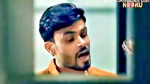 Handsome bearded Indian man with blue hair in orange shirt looking sideways seductively