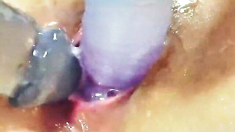 Close-up of Asian woman masturbating with two purple dildos inserted